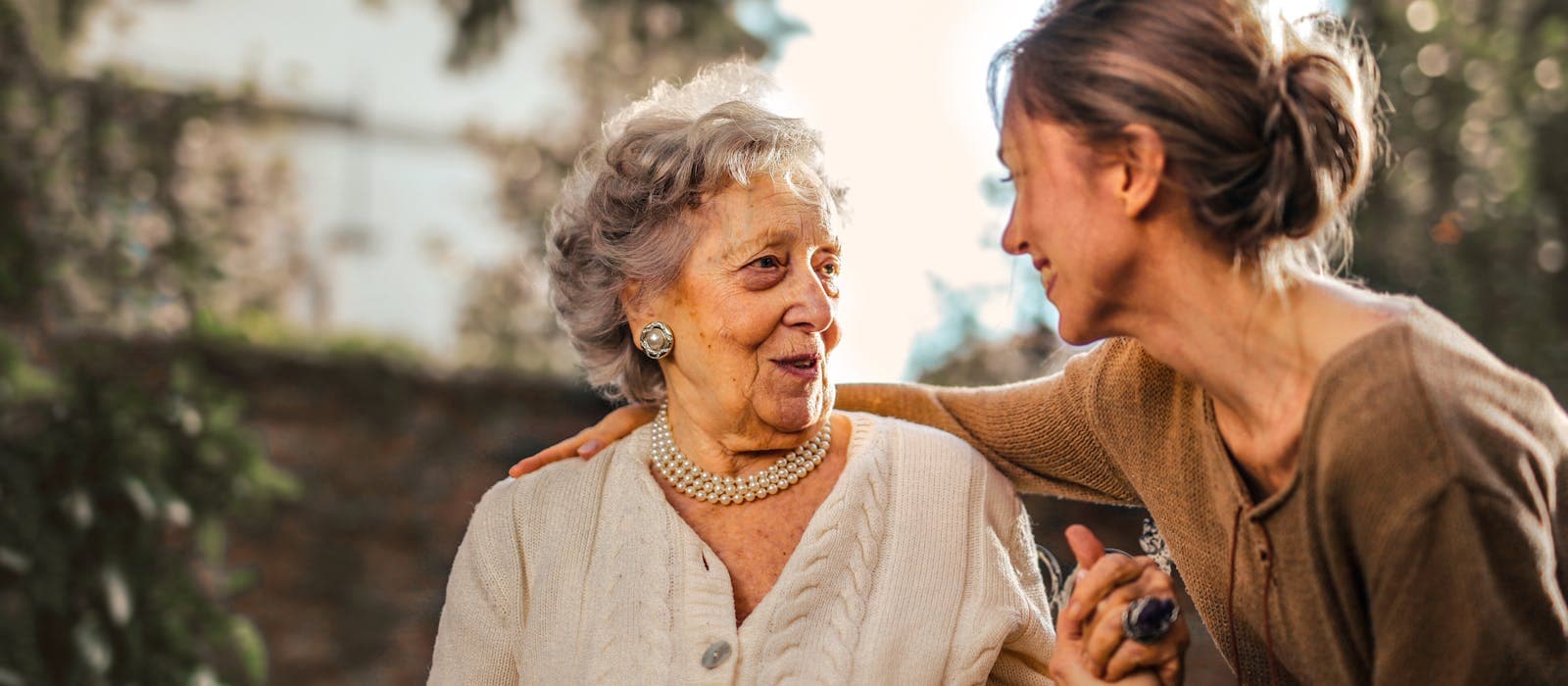 A companion sharing a warm moment with a senior woman outdoors
